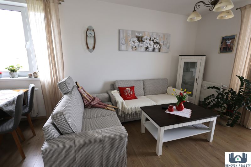 Living room in a 2-room apartment with a comfortable sofa, a table, and a wooden decor floor.