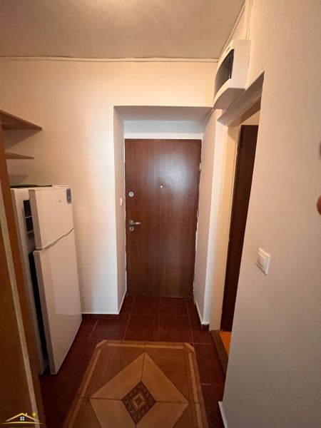 Entrance to a studio apartment with a refrigerator and a wooden decor floor.