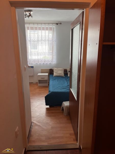 In the studio apartment, there is a blue bed, a nightstand, and a floor with a wooden decor.