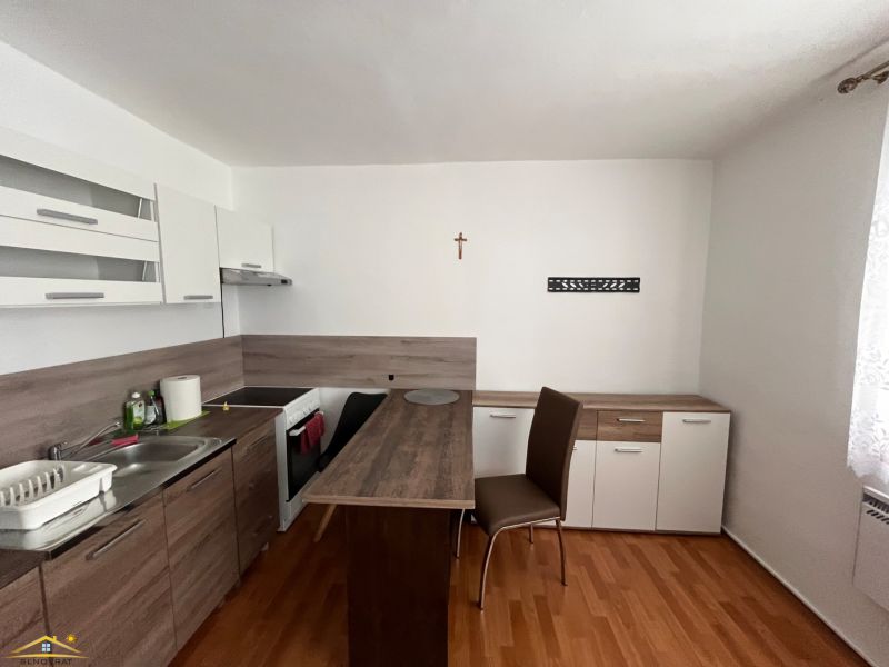 Studio apartment with a kitchenette and a wooden decor floor and a dining table.