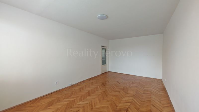 An empty room with a wooden floor and white walls in a two-room apartment.