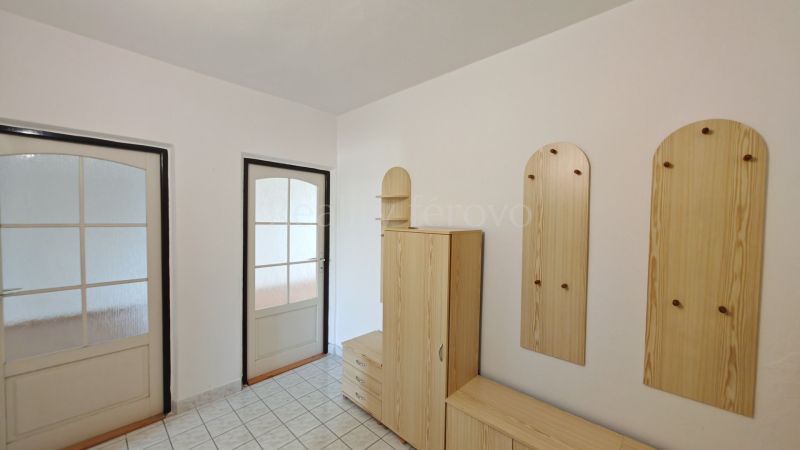 Hallway of a 2-room apartment with wooden storage furniture and glass doors.