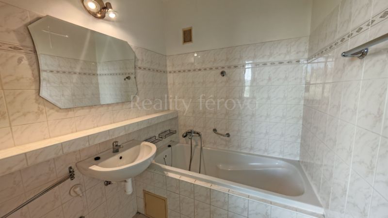 Bathroom in a 2-room apartment with a bathtub, sink, and white tiles.