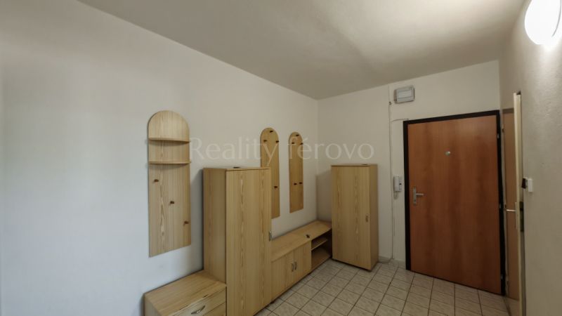 A hallway in a 2-room apartment with light furniture and tiled flooring.