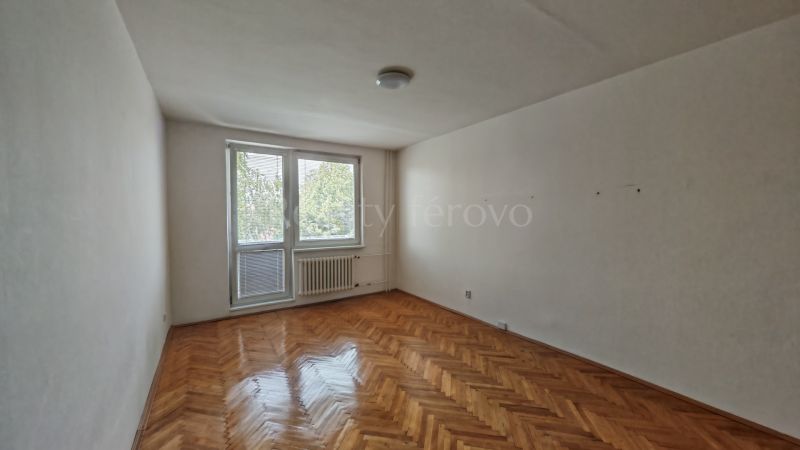 Living room in a two-room apartment with a wooden decor floor and a balcony.