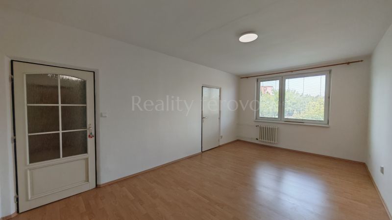 A spacious room in a 2-room apartment with a wooden decor floor and a large window.