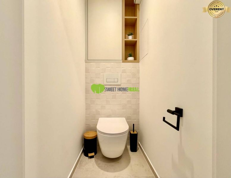A minimalist bathroom in a 2-room apartment with a toilet and simple shelves.