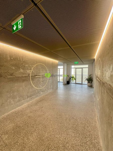 A corridor in an apartment building with concrete walls and emergency exit signs.