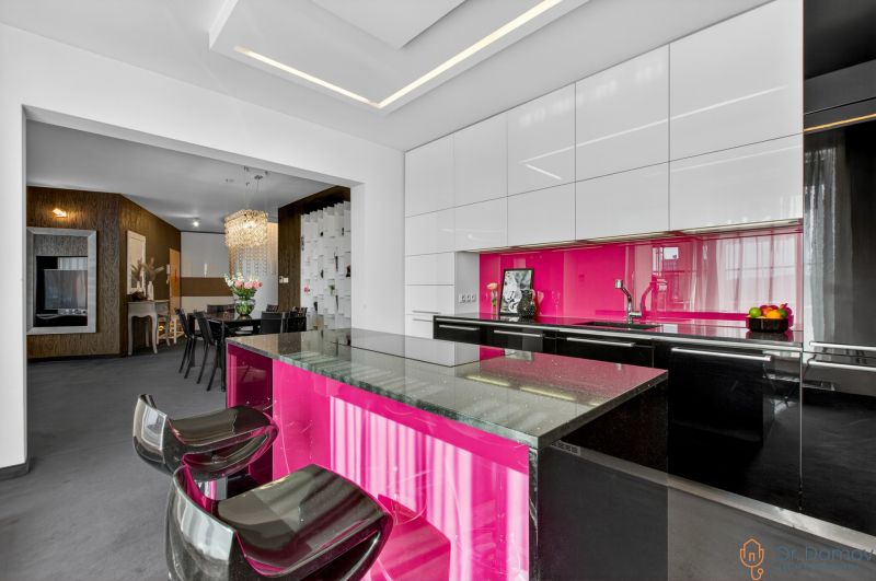 The kitchen of a 4-room apartment with a bright pink cabinet and stylish chairs.