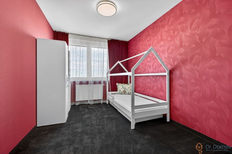 A children's room with red walls, white furniture, and a window in a 4-room apartment.