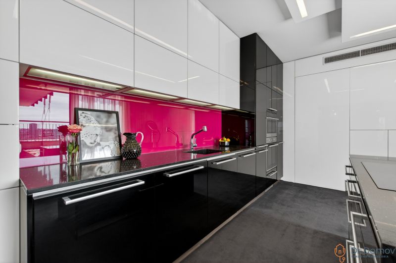 A kitchen in a 4-room apartment with black cabinets and pink tiles.