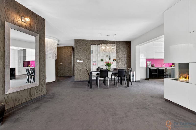 Dining room in a 4-room apartment with a mirror, fireplace, and kitchen with pink tiles.