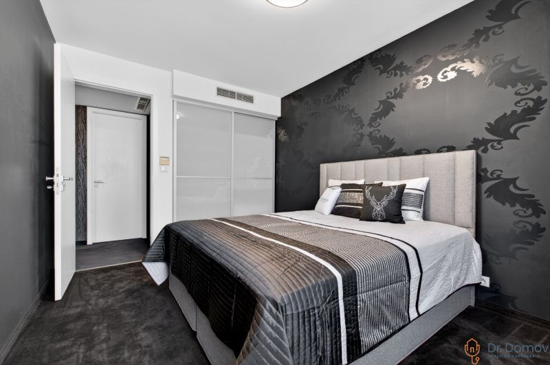 Bedroom in a 4-room apartment with patterned black wallpaper and a comfortable bed.