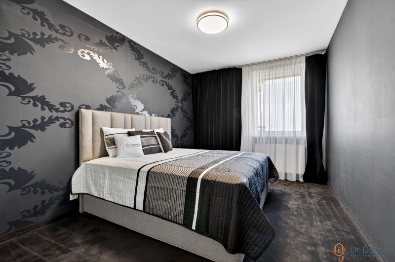 A bedroom with patterned wallpaper, a large bed, and dark curtains in a 4-room apartment.