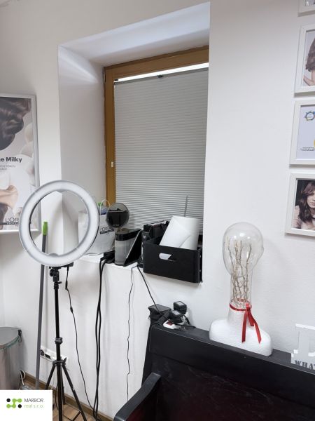 Hair salon with a ring light, mannequin head, and decorative pictures on the walls.