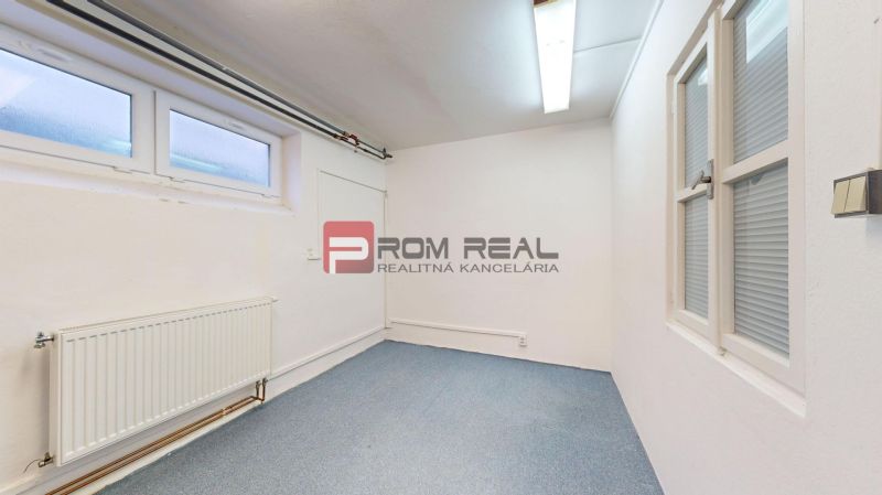 A room with white walls, a blue carpet, and windows. Warehouses and halls.