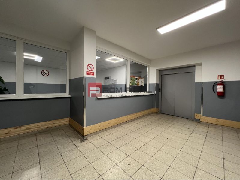 Interior of a building with a staircase and an elevator, warehouses and halls, tiles, light gray walls.