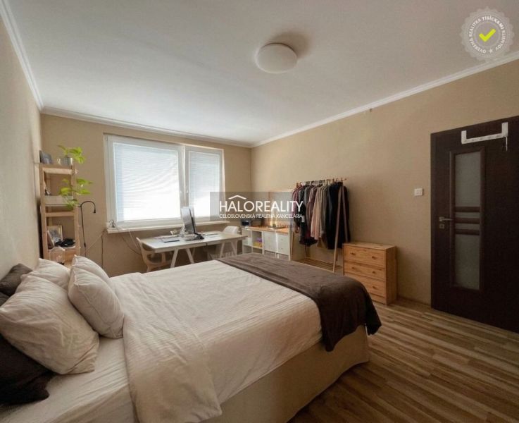 A bedroom in a 3-room apartment with a bed, a desk, and a wooden decor floor.