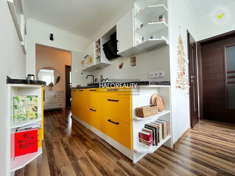 A kitchen with yellow cabinets and a wood-patterned floor in a 3-room apartment.