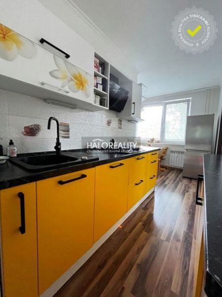 A kitchen with dominant yellow cabinets and a wooden decor floor in a 3-room apartment.