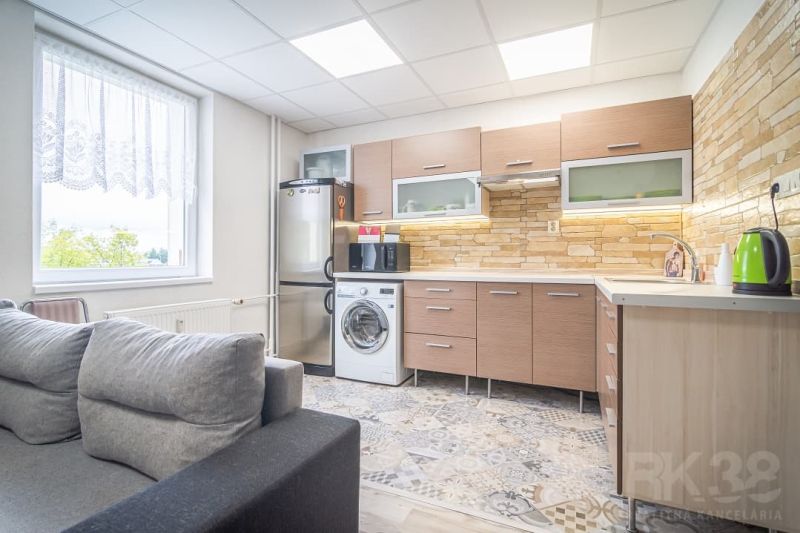 A kitchen in a 2-room apartment with stone cladding and a wooden decor floor.
