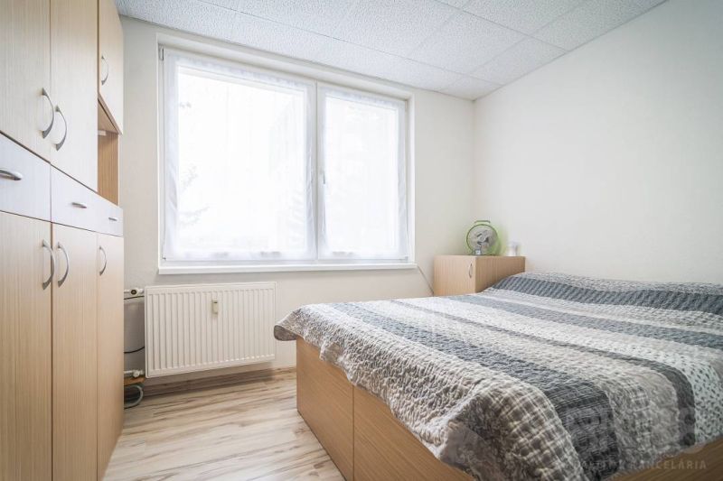 Bedroom in a 2-room apartment with wardrobes and a bed, floor with wood decor.