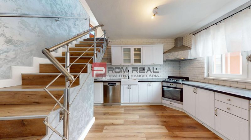 A kitchen in a family house with white cabinets, a stainless steel dishwasher, and a wooden-patterned floor.