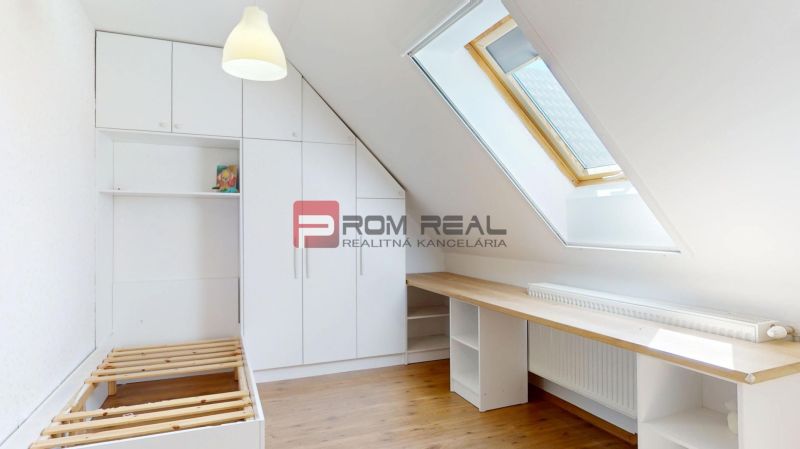 A bright attic room with a bed, a built-in wardrobe, and a floor with a wood decor.