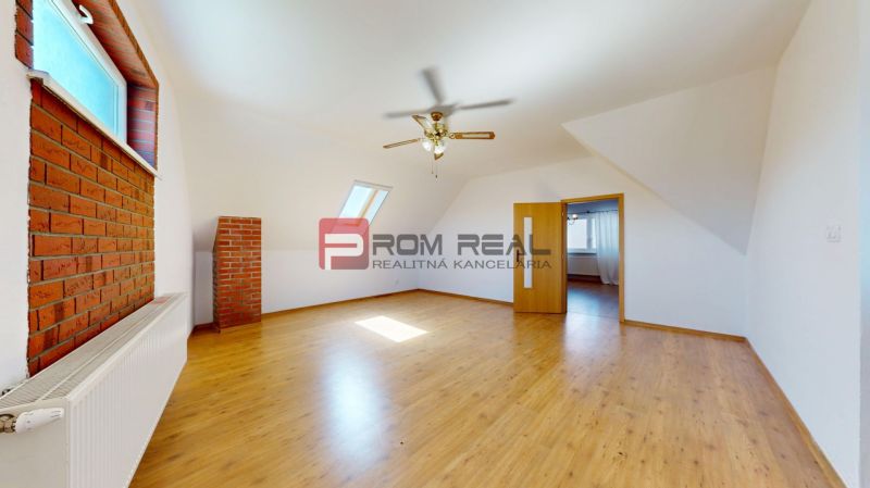 A room in a family house with a wooden decor floor and a brick wall cladding.