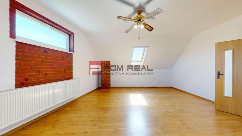 A room in a family house with a wooden decor floor, a skylight, and brick cladding.