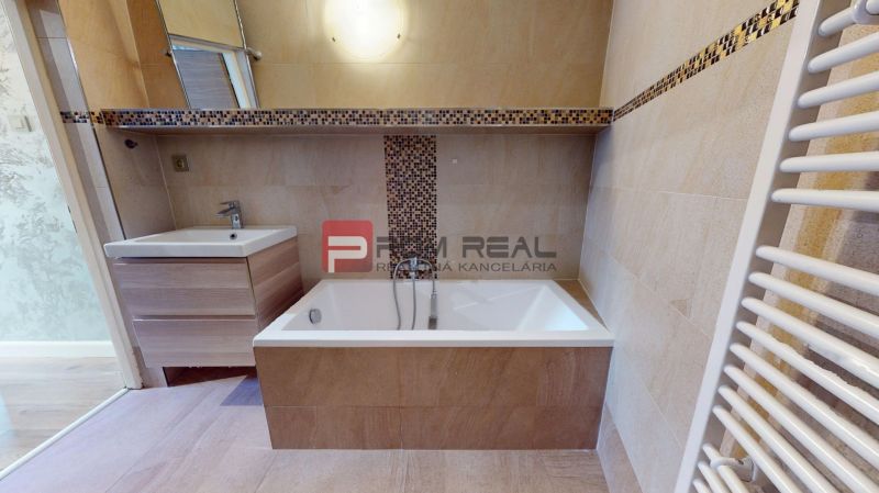 A bathroom in a family house with a bathtub, sink, and designer tiles.