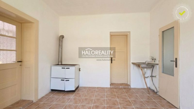 A room in a family house with ceramic tiles, a stove, and a sink.