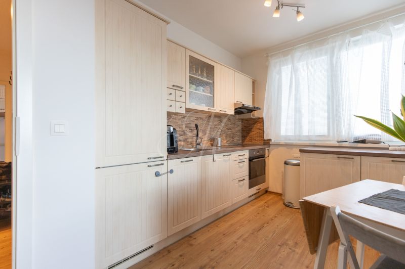 A bright kitchen with a kitchen unit and a wooden decor floor in a 2-room apartment.