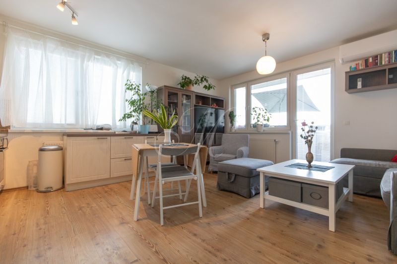 Bright living room with wood-patterned flooring, a table, and comfortable seating.