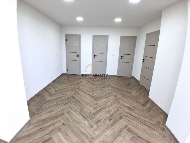 Interior of commercial premises with three doors and a wooden decor floor.