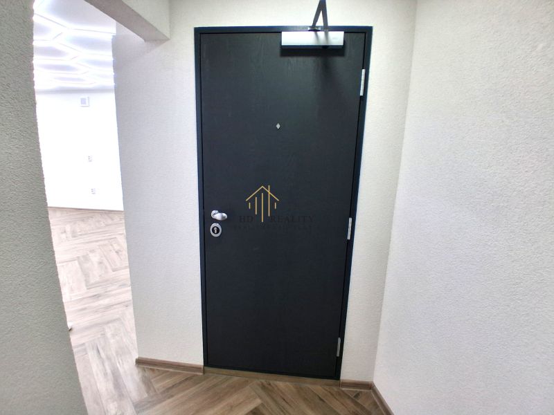 Black doors in commercial premises with wood-patterned flooring and white walls.