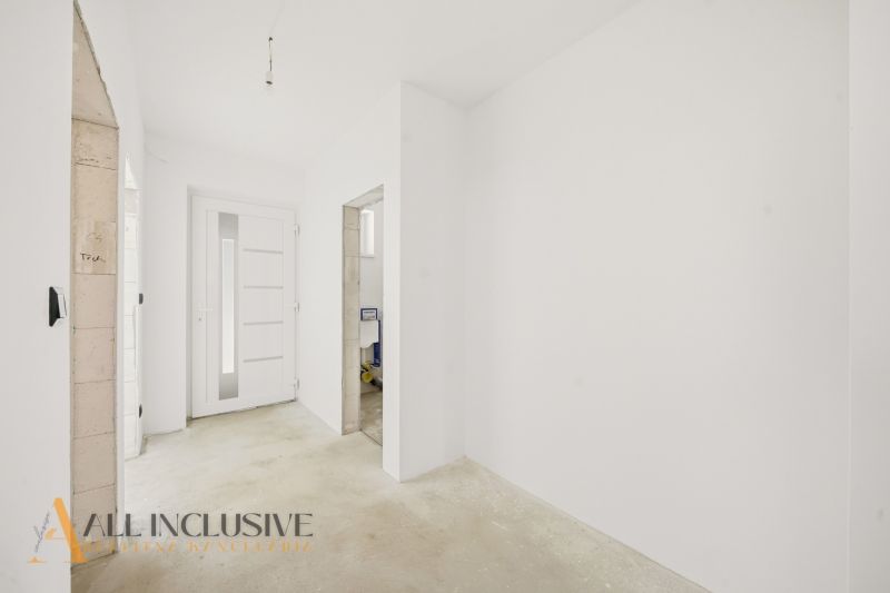 A hallway in a family house with white walls and white doors.