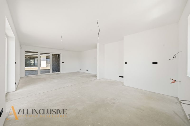 A spacious room in a family house with bare walls and a floor without covering.