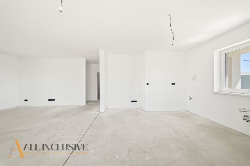 White room with a window and concrete floor in a family house.