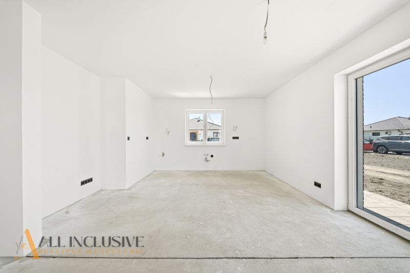 A spacious unfurnished interior room in a family house with a view of the exterior.