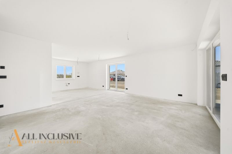 Spacious room with white walls and an empty floor, living area of a family house.