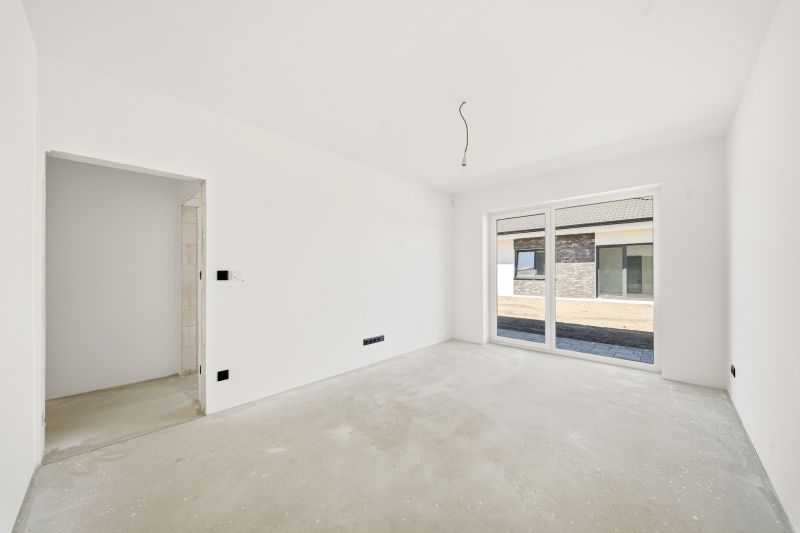 A spacious room in a family house with windows and white walls.