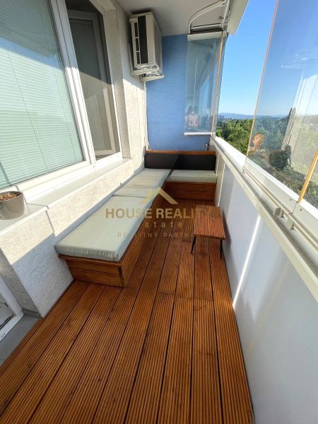 Balcony of a 2-room apartment with seating and flooring with a wooden decor.