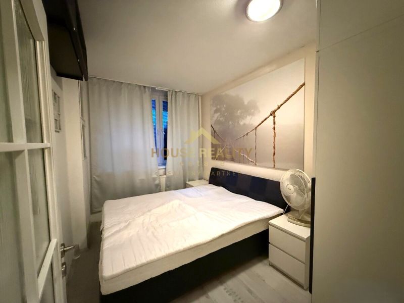 Bedroom in a 2-room apartment with a large bed and a wall picture of a bridge.