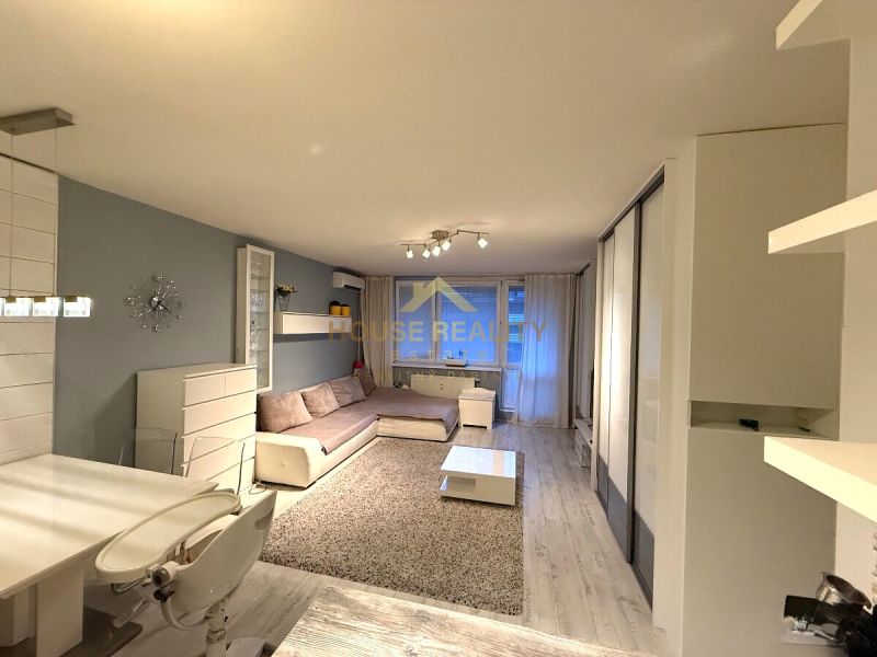 Living room in a two-room apartment with white furniture and a sofa, wooden decor flooring.