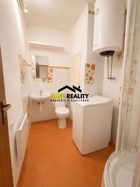 A bathroom in a studio apartment with a washing machine, toilet, and boiler.