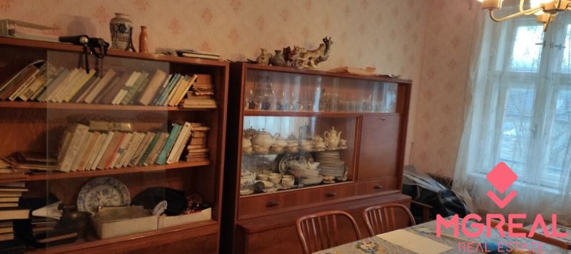 Dining room in a family house with a showcase full of porcelain and books on wooden shelves.