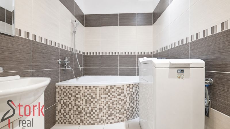 A bathroom in a 3-room apartment with a bathtub, sink, and washing machine.