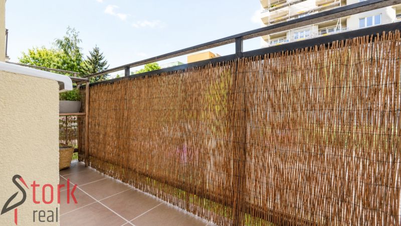 Balcony of a 3-room apartment with rattan screening, ceramic flooring, view of the surroundings.