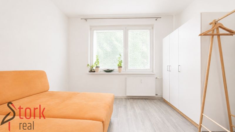 A room in a 3-room apartment with an orange sofa and a white wardrobe.